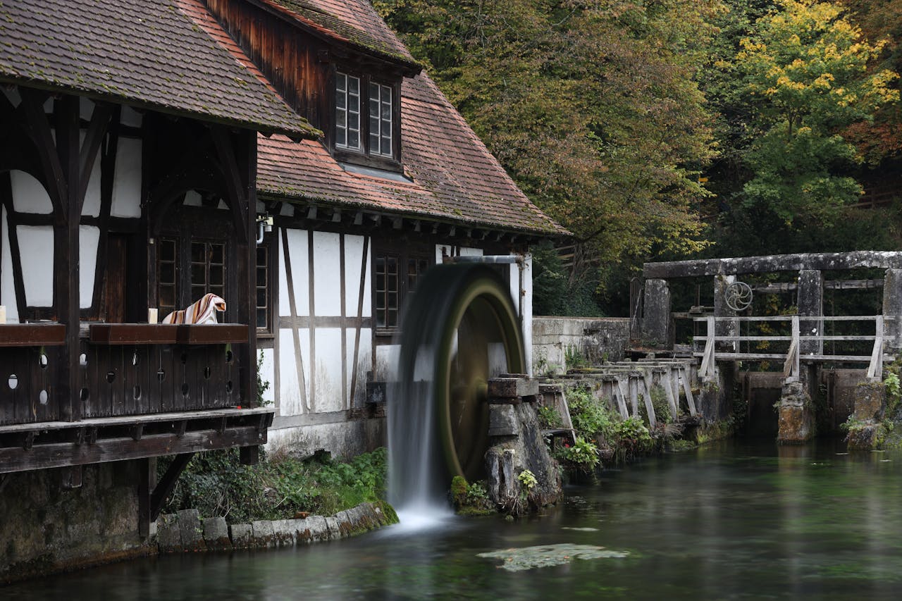 Peaceful scene of an old watermill by a river in autumn, showcasing natures beauty.
