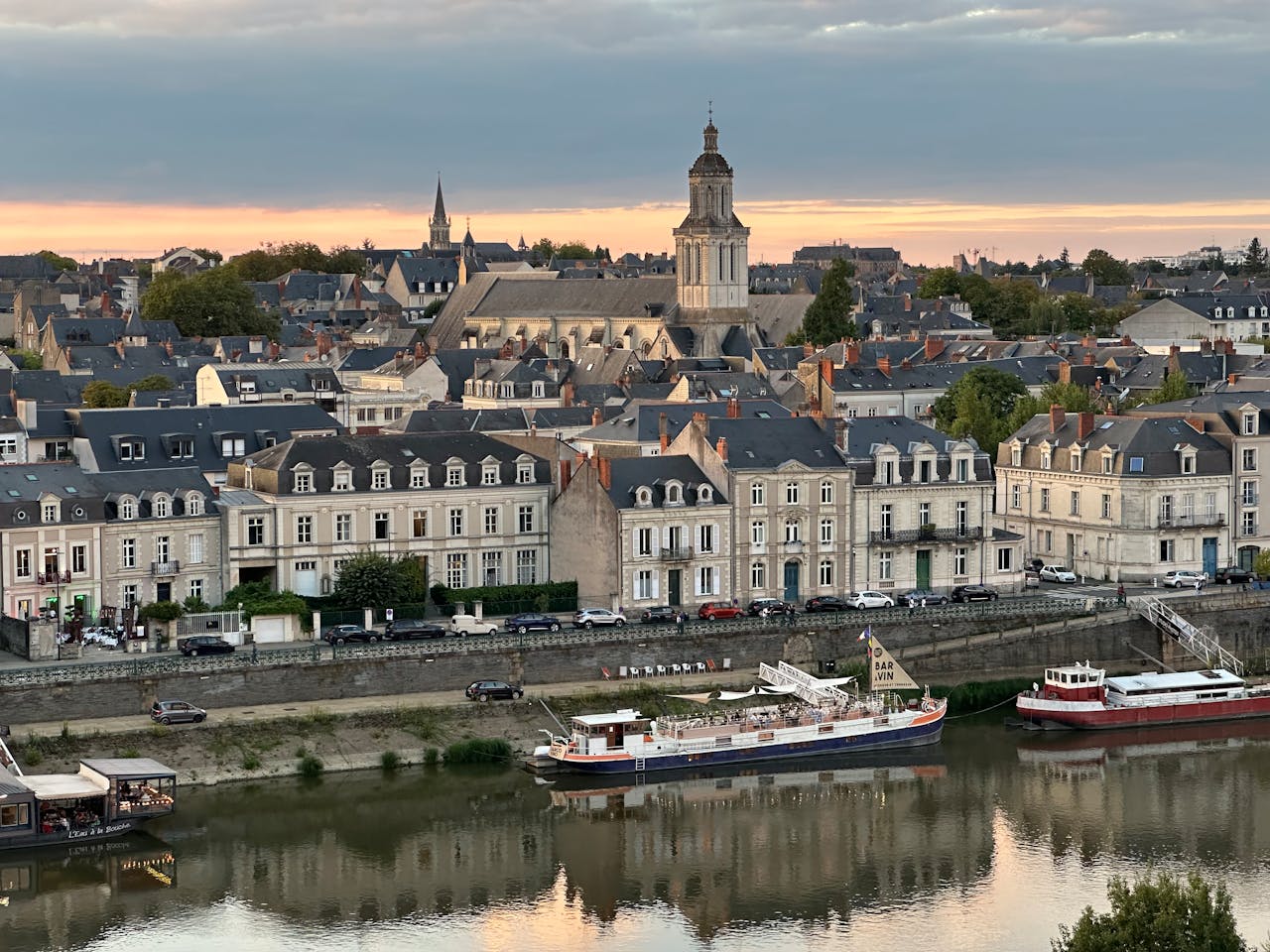 why-choose-us Historic cityscape of Angers, France, featuring charming architecture along the river at sunset.