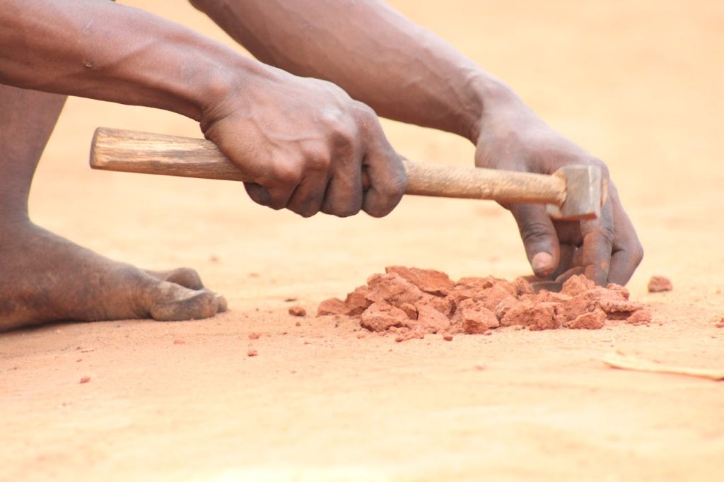 Crafting Captivating Headlines: Your awesome post title goes here Close-up of a craftsman in Abomey, Benin, breaking clay with a hammer, showcasing traditional skills.